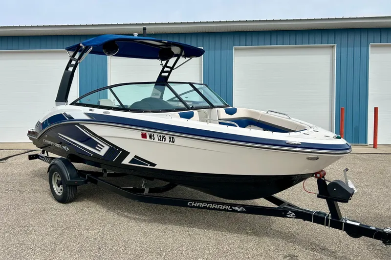 Slide: The Image of 2017 Chaparral 203 Vortex boat on trailer, blue and white design, parked outdoors. - 2