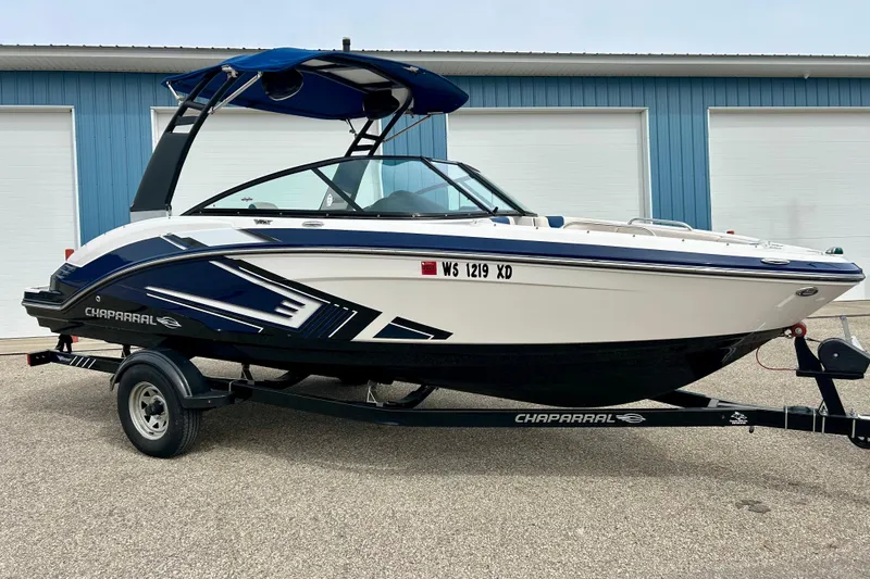 Slide: The Image of 2017 Chaparral 203 Vortex boat on trailer, blue and white design, parked outdoors. - 4