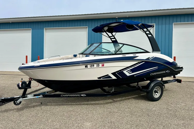 Slide: The Image of 2017 Chaparral 203 Vortex boat on trailer, parked near blue building. - 6