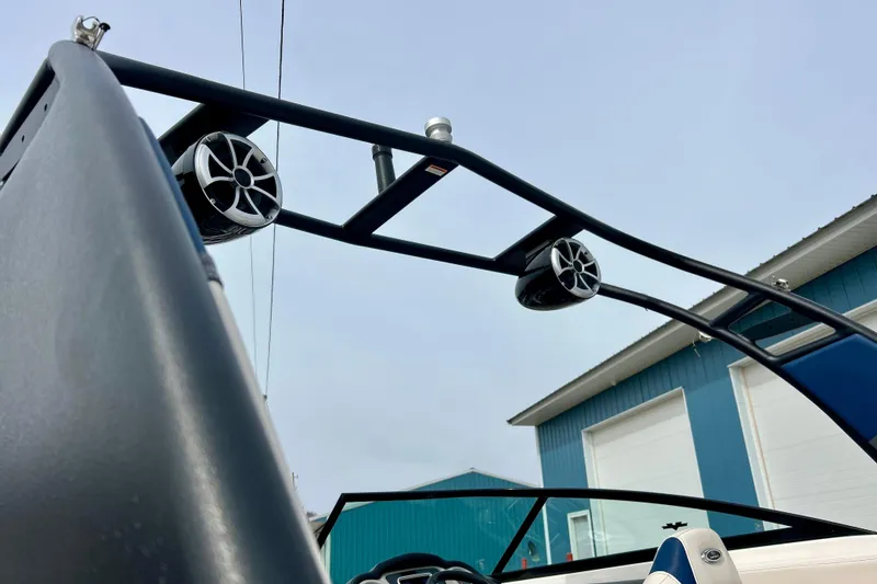 Slide: The Image of 2017 Chaparral 203 Vortex boat with speakers on wakeboard tower, blue building background. - 84