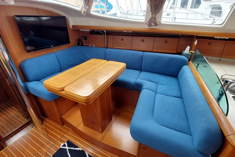 Slide: The Image of Interior of 2002 Jeanneau Sun Odyssey 43 DS with blue seating and wooden table. - 63