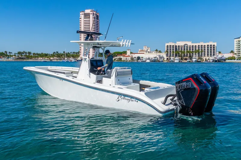 Slide: The Image of 2014 Yellowfin 29 Offshore boat on clear blue water near a coastal cityscape. - 13