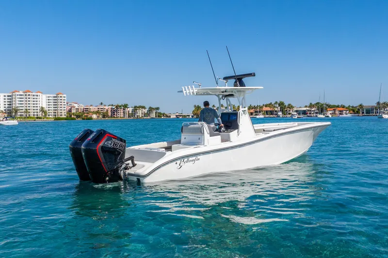 Slide: The Image of 2014 Yellowfin 29 Offshore boat cruising on clear blue water near coastal buildings. - 15