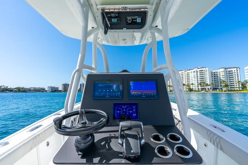 Slide: The Image of 2014 Yellowfin 29 Offshore boat dashboard with modern controls, overlooking waterfront buildings. - 23