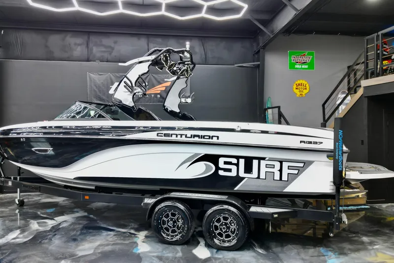 Slide: The Image of 2017 Centurion Ri237 surf boat in showroom, featuring sleek design and modern graphics. - 2
