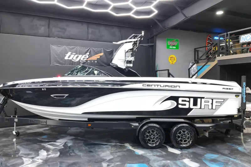 Slide: The Image of 2017 Centurion Ri237 surf boat displayed indoors on a trailer. - 32