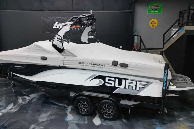 Slide: The Image of 2017 Centurion Ri237 surf boat covered in a garage, showcasing sleek design and branding. - 5