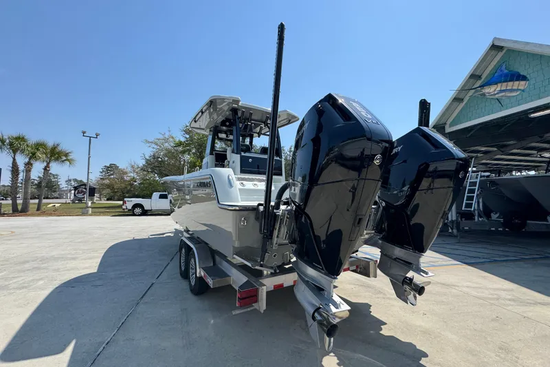 Slide: The Image of 2026 Caymas 29 CT boat with dual outboard motors on a trailer in a marina. - 16