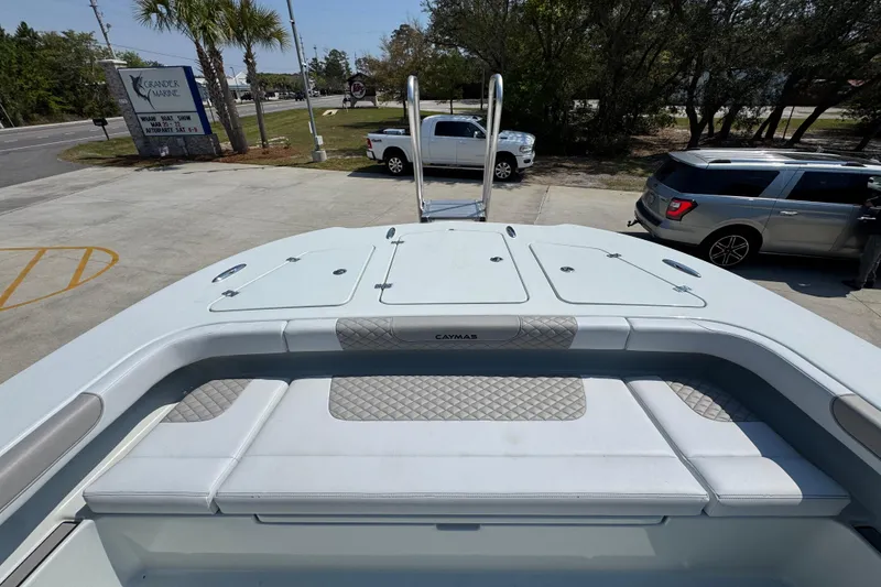 Slide: The Image of 2026 Caymas 29 CT boat with cushioned seating, parked near vehicles and palm trees. - 23