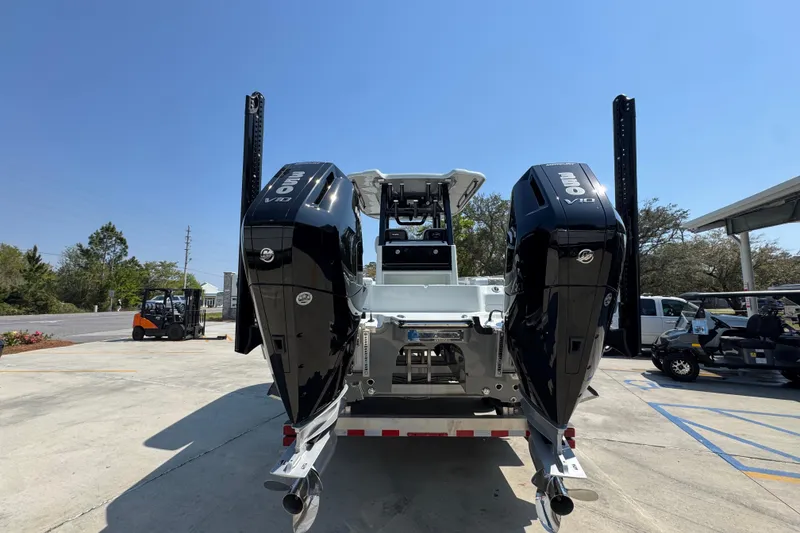 Slide: The Image of 2026 Caymas 29 CT boat with dual powerful outboard engines, parked outdoors. - 15