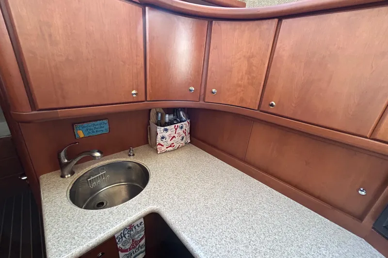 Slide: The Image of 2005 Silverton 38 Convertible yacht kitchen with wooden cabinets and a compact sink. - 15