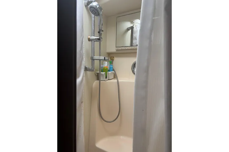 Slide: The Image of Shower area inside 2005 Silverton 38 Convertible yacht, featuring handheld showerhead and toiletries. - 18