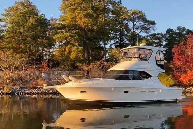 Slide: The Image of 2005 Silverton 38 Convertible yacht on calm water, surrounded by autumn trees. - 2