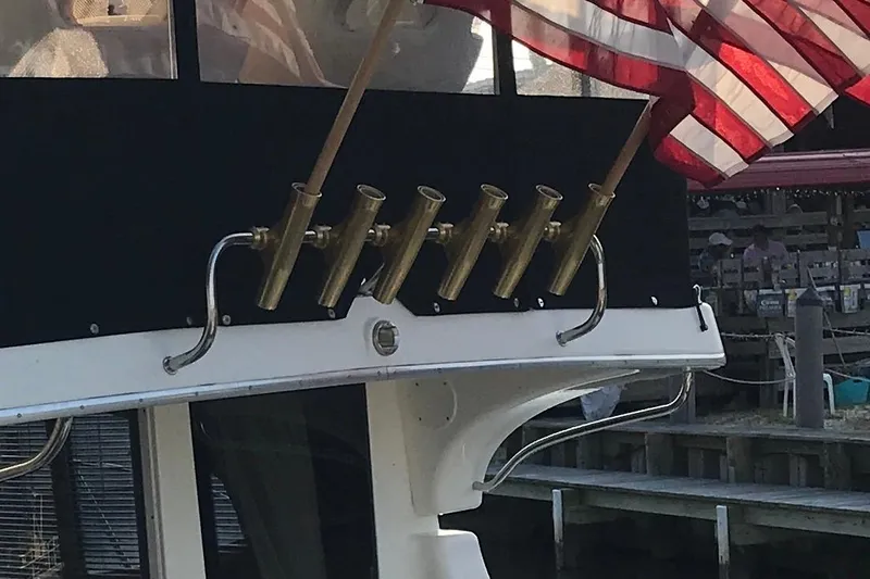 Slide: The Image of 2005 Silverton 38 Convertible boat with rod holders and American flag at dock. - 6