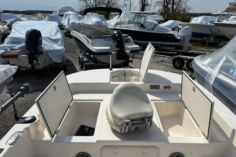 Slide: The Image of 2023 Carolina Skiff 21 LS boat with open storage compartments, parked among other boats. - 13