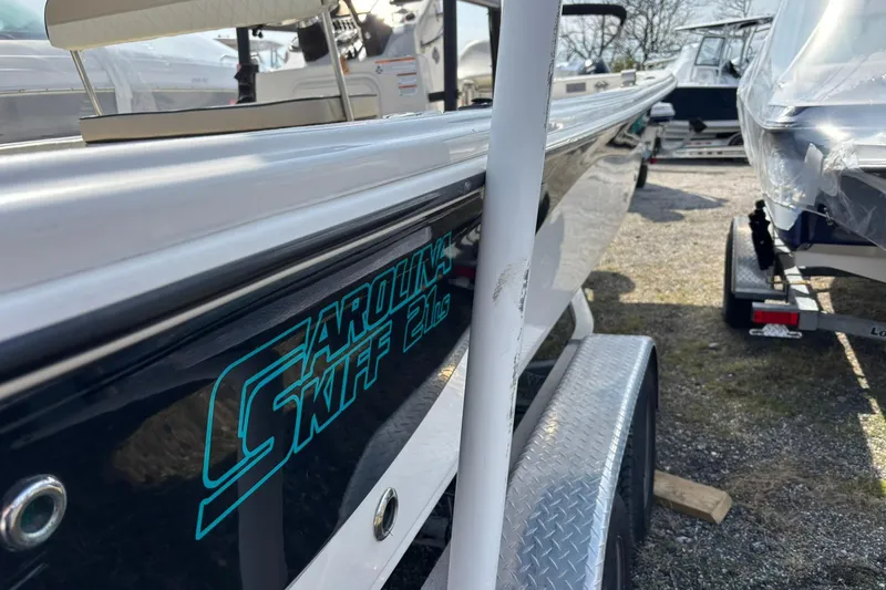 Slide: The Image of 2023 Carolina Skiff 21 LS boat on trailer, side view with logo visible. - 2