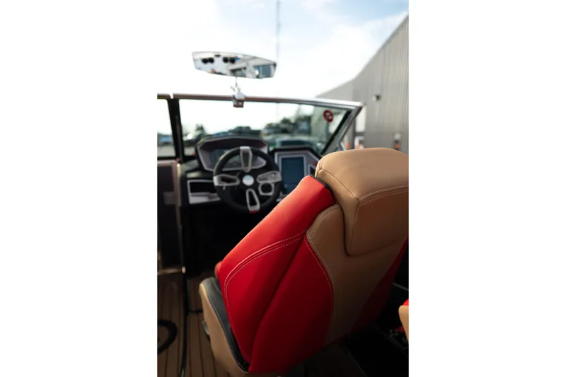 Slide: The Image of 2021 MasterCraft X24 boat interior with red and tan seating, steering wheel, and dashboard. - 34