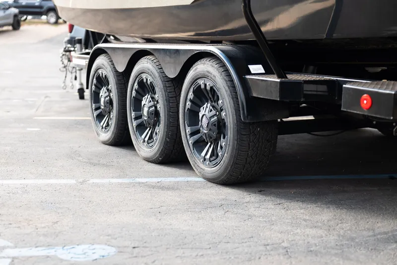 Slide: The Image of Triple-axle trailer for 2021 MasterCraft X24 boat, parked on asphalt. - 43