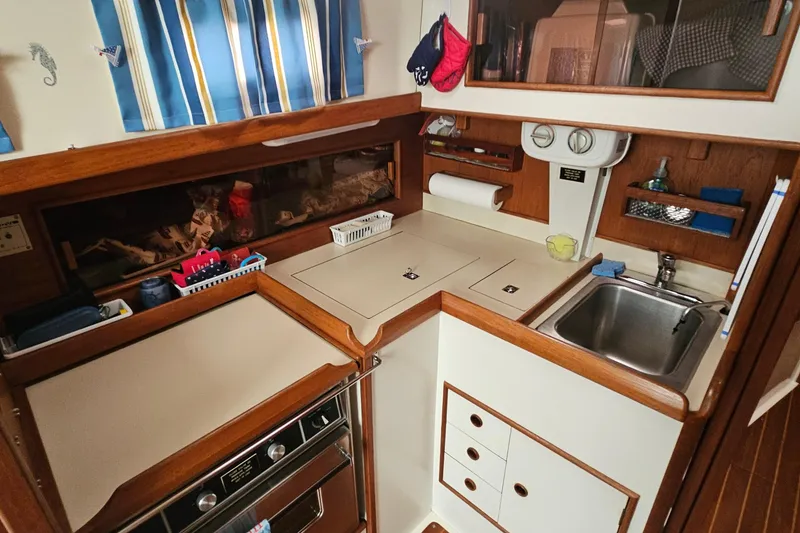 Slide: The Image of Compact galley kitchen in a 1985 Nonsuch 30 sailboat with wood accents and striped curtains. - 4