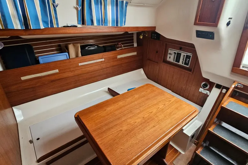 Slide: The Image of Interior of a 1985 Nonsuch 30 sailboat with wooden table and striped curtains. - 5