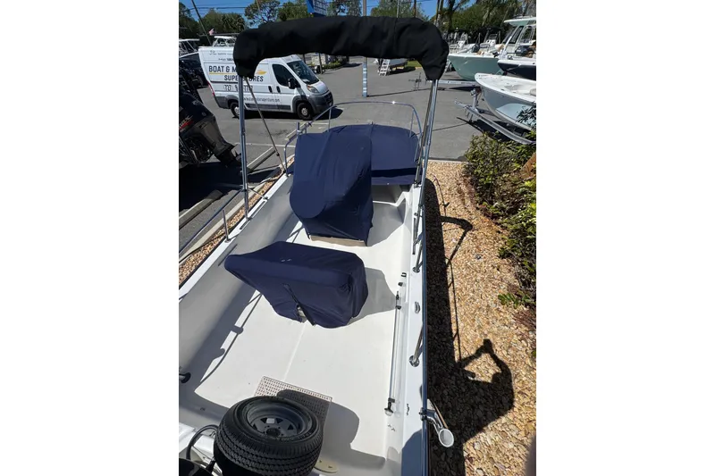 Slide: The Image of 2003 Boston Whaler 170 Montauk boat with covered seats and canopy in a marina. - 17