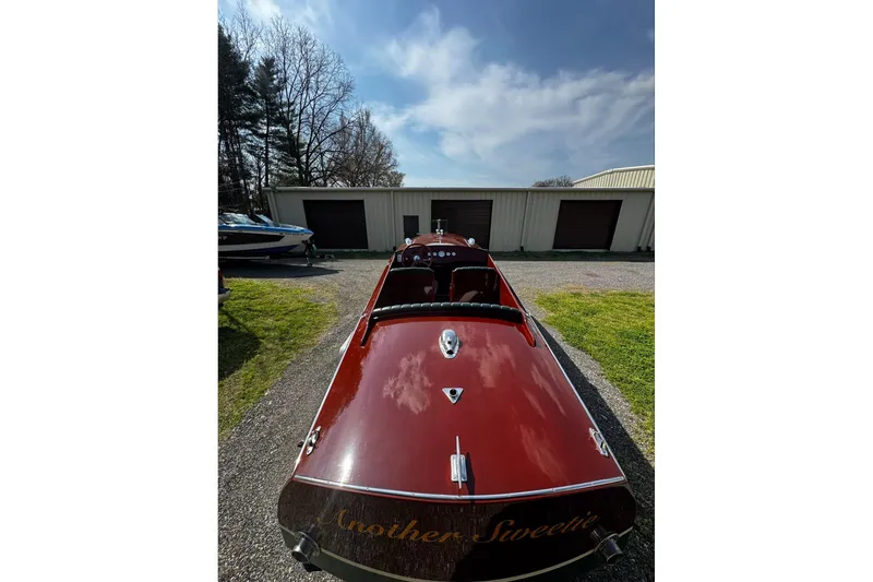 Slide: The Image of 2014 Hacker-Craft 26' Runabout boat parked outdoors, showcasing sleek wooden design. - 16