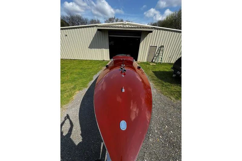 Slide: The Image of 2014 Hacker-Craft 26' Runabout boat outside a metal garage under a blue sky. - 17