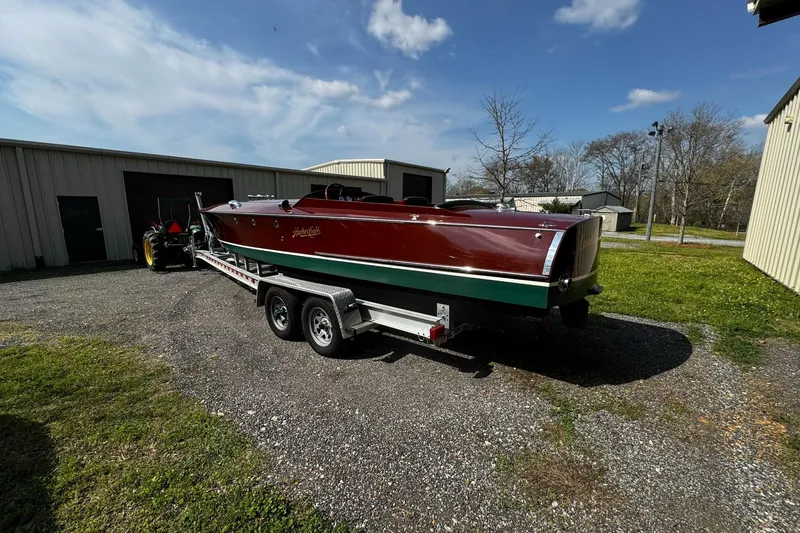 Slide: The Image of 2014 Hacker-Craft 26' Runabout on trailer, parked outdoors near storage buildings. - 3