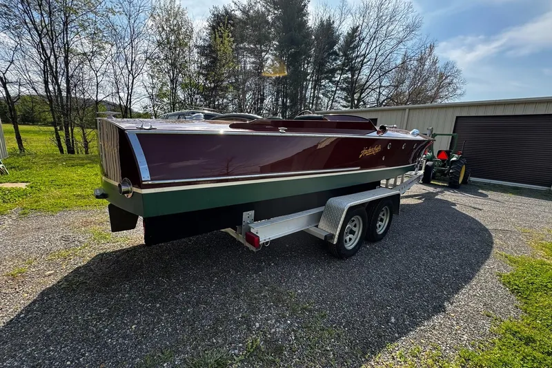 Slide: The Image of 2014 Hacker-Craft 26' Runabout on trailer, parked outdoors near trees and a building. - 6