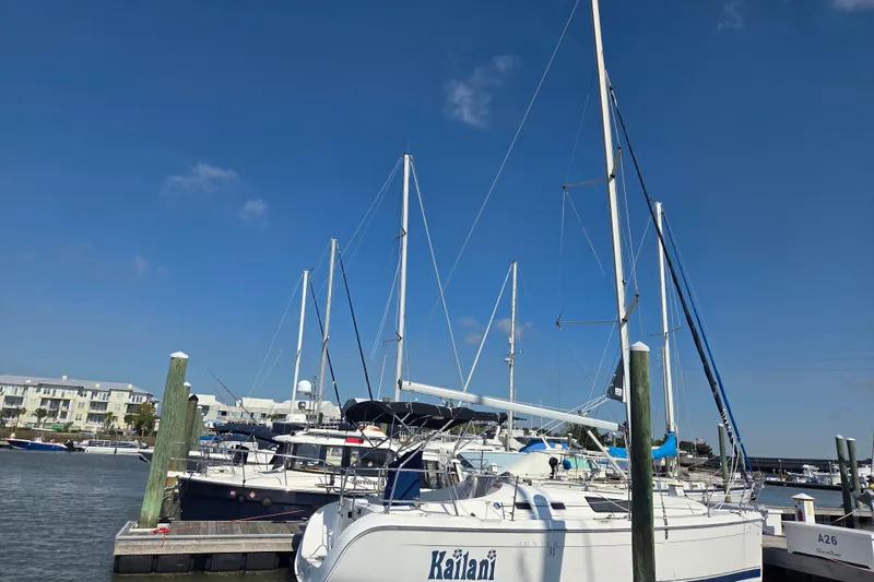Slide: The Image of Sailboats docked at a marina under a clear blue sky, featuring a 2005 Hunter 31. - 23