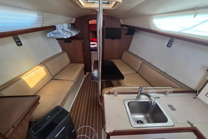 Slide: The Image of Interior of a 2005 Hunter 31 sailboat with beige seating and compact kitchen area. - 3