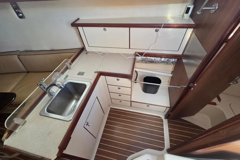 Slide: The Image of Compact kitchen area in a 2005 Hunter 31 sailboat with sink and storage cabinets. - 4