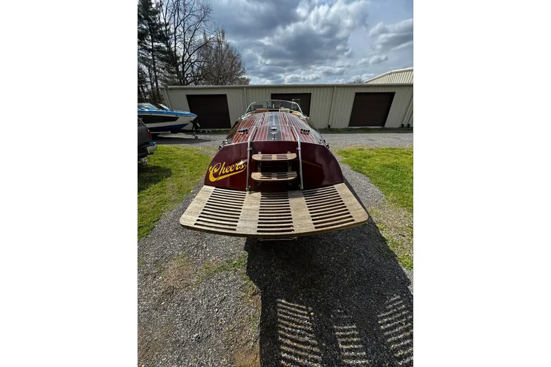 Slide: The Image of 2016 Hacker-Craft 28 Sport boat with "Cheers" text, parked outdoors under cloudy sky. - 11