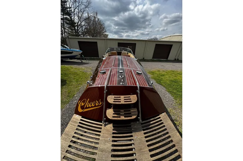 Slide: The Image of 2016 Hacker-Craft 28 Sport boat with wooden deck, parked outdoors under cloudy sky. - 7