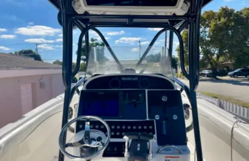 Slide: The Image of 2006 Wellcraft 32 CCF boat dashboard with steering wheel and controls under clear blue sky. - 30