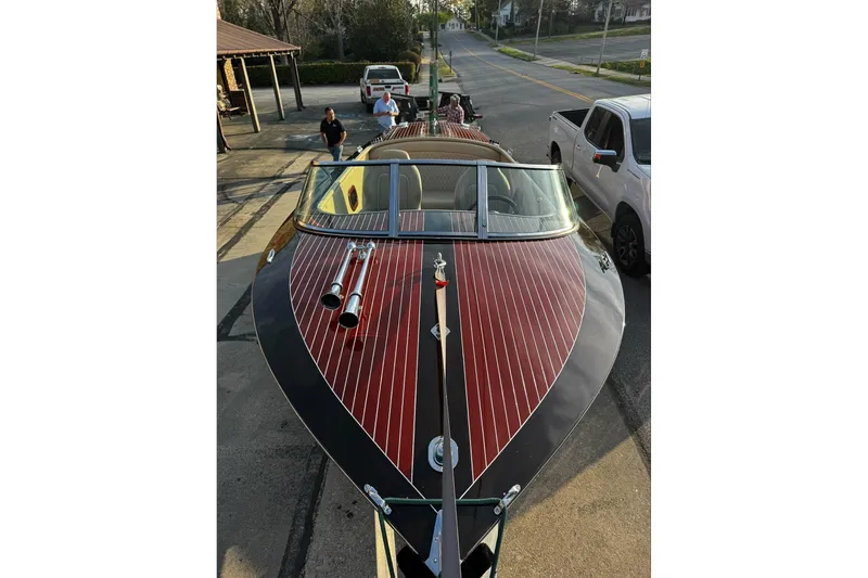 Slide: The Image of 2019 Hacker-Craft 23 Runabout boat with polished wood finish, parked on a street. - 17