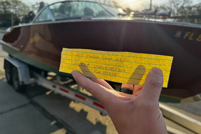 Slide: The Image of Hand holding note in front of 2019 Hacker-Craft 23 Runabout boat on trailer. - 29