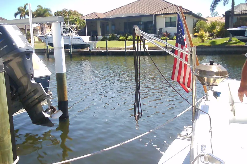 Slide: The Image of Boat docked by waterfront home, featuring American flag and grill, Sabre 34, 1999 model. - 16