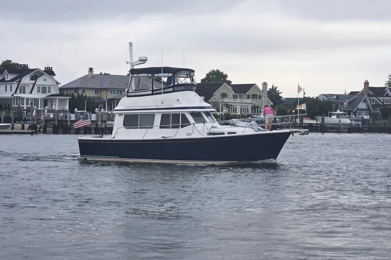 The Image of 1999 Sabre 34 yacht cruising near waterfront homes on a cloudy day. - 0