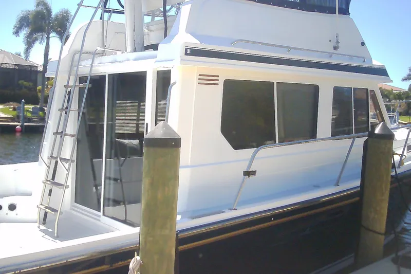 Slide: The Image of 1999 Sabre 34 boat docked, featuring a sleek white exterior and ladder access. - 14