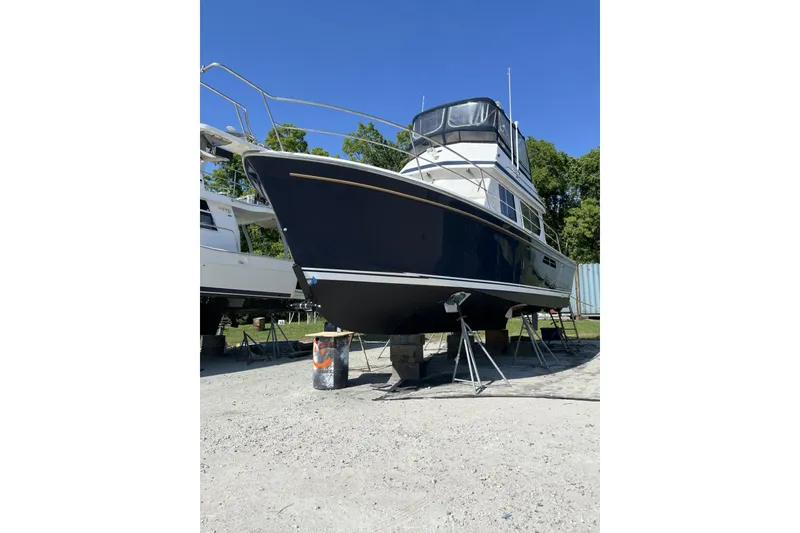 Slide: The Image of 1999 Sabre 34 boat on stands, blue hull, clear sky background. - 15