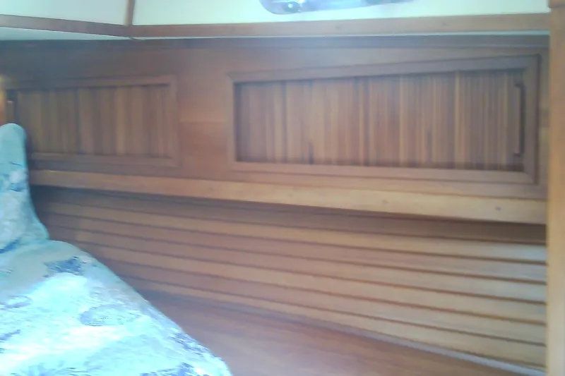 Slide: The Image of Interior of a 1999 Sabre 34 yacht with wooden paneling and a patterned bedspread. - 62