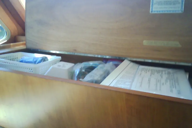 Slide: The Image of Wooden storage compartment in a 1999 Sabre 34 boat, containing documents and items. - 69