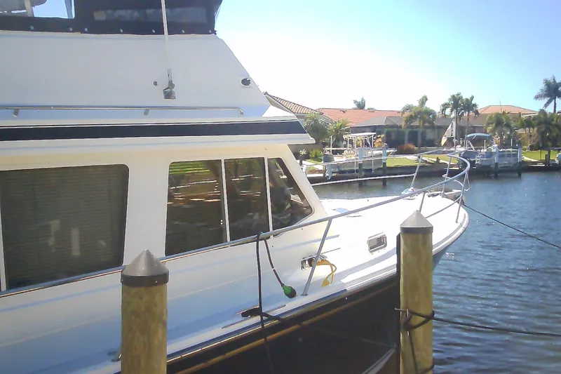 Slide: The Image of 1999 Sabre 34 yacht docked by waterfront homes, sunny day, palm trees in background. - 7