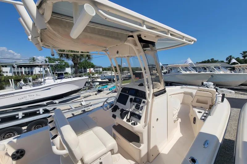 Slide: The Image of 2019 Grady-White 251 Coastal Explorer boat interior with helm and seating, docked under clear skies. - 13