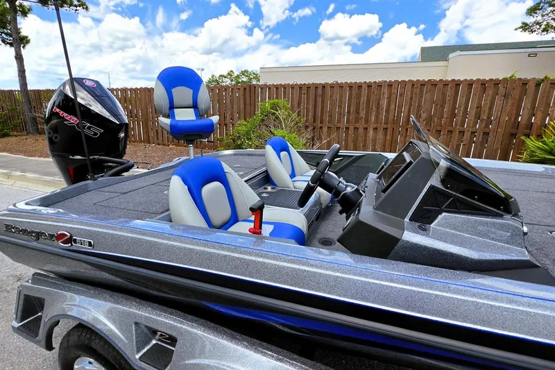 Slide: The Image of 2026 Ranger Z518 Cup-Equipped boat with blue and white seating, parked outdoors. - 13