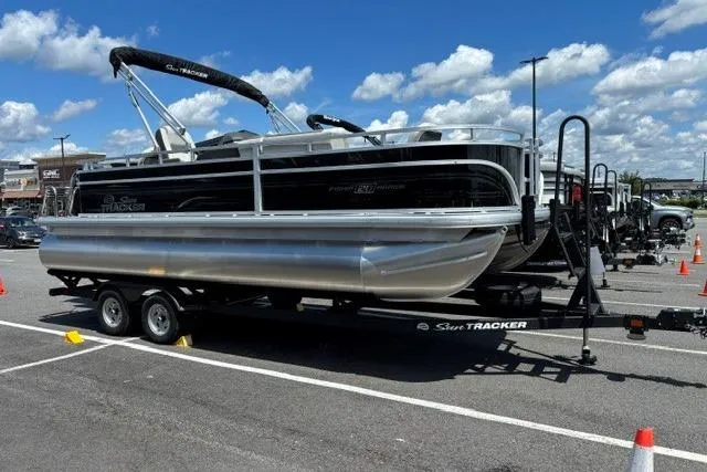The Image of 2026 Sun Tracker Fishin' Barge 20 DLX pontoon boat on trailer in parking lot. - 0