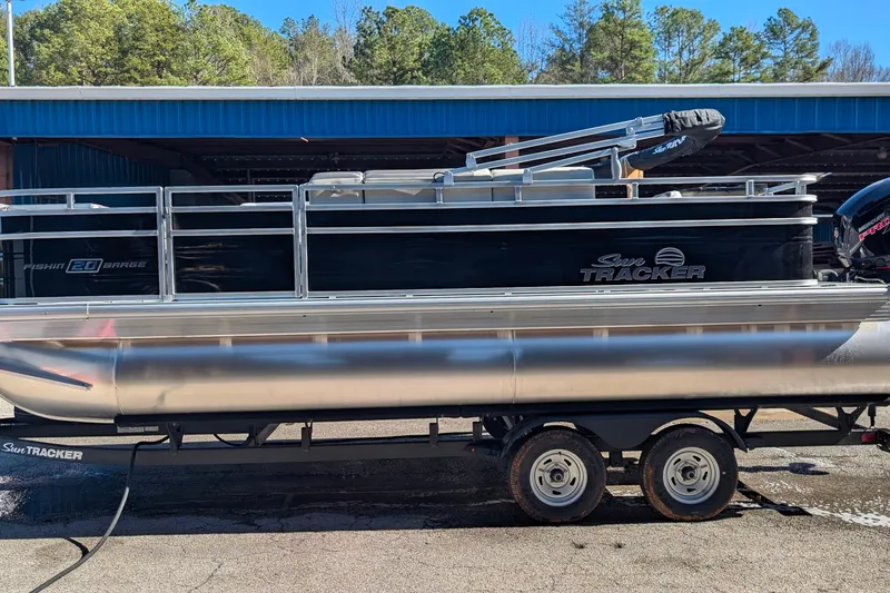 The Image of 2026 Sun Tracker Fishin' Barge 20 DLX pontoon boat on trailer, parked outdoors. - 0