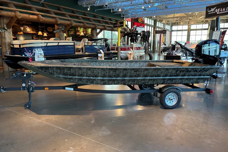 The Image of 2026 Tracker Grizzly 1648 Utility boat displayed in a showroom on a trailer. - 0