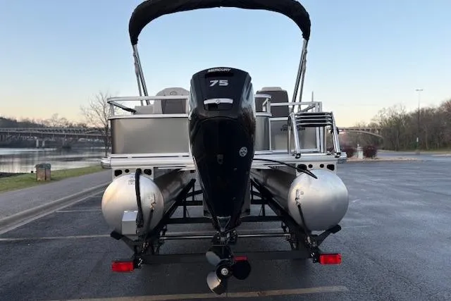 Slide: The Image of 2026 Sun Tracker Bass Buggy 18 DLX pontoon boat with Mercury 75 engine, parked by a river. - 105